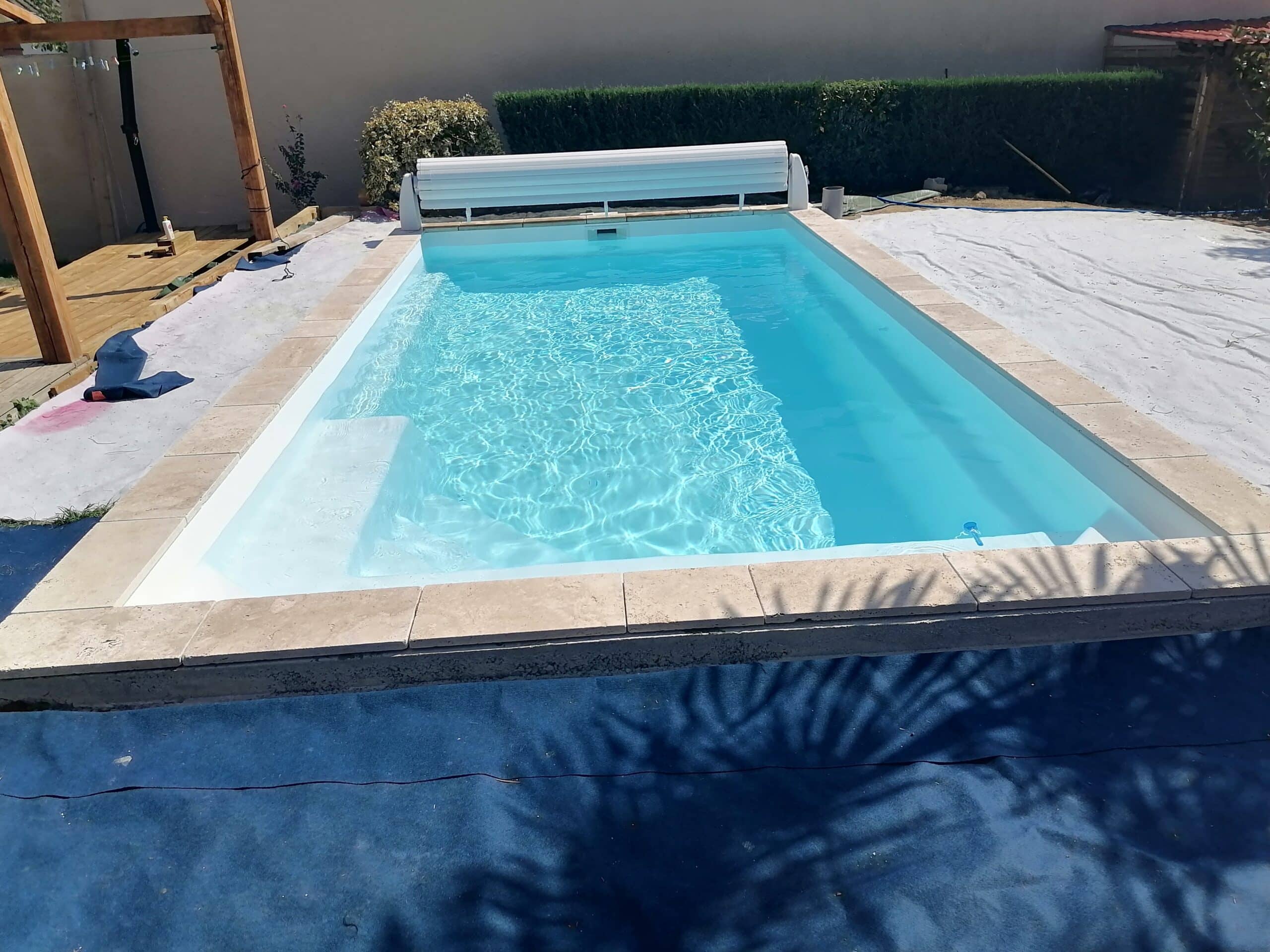 Piscine Rectangulaire avec Volet Roulant et Margelles Piscine rectangulaire moderne avec eau turquoise cristalline, margelles en pierre et volet roulant automatique blanc.